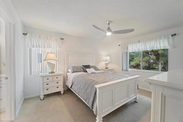 a spacious bedroom with a bed a lamp and a dresser