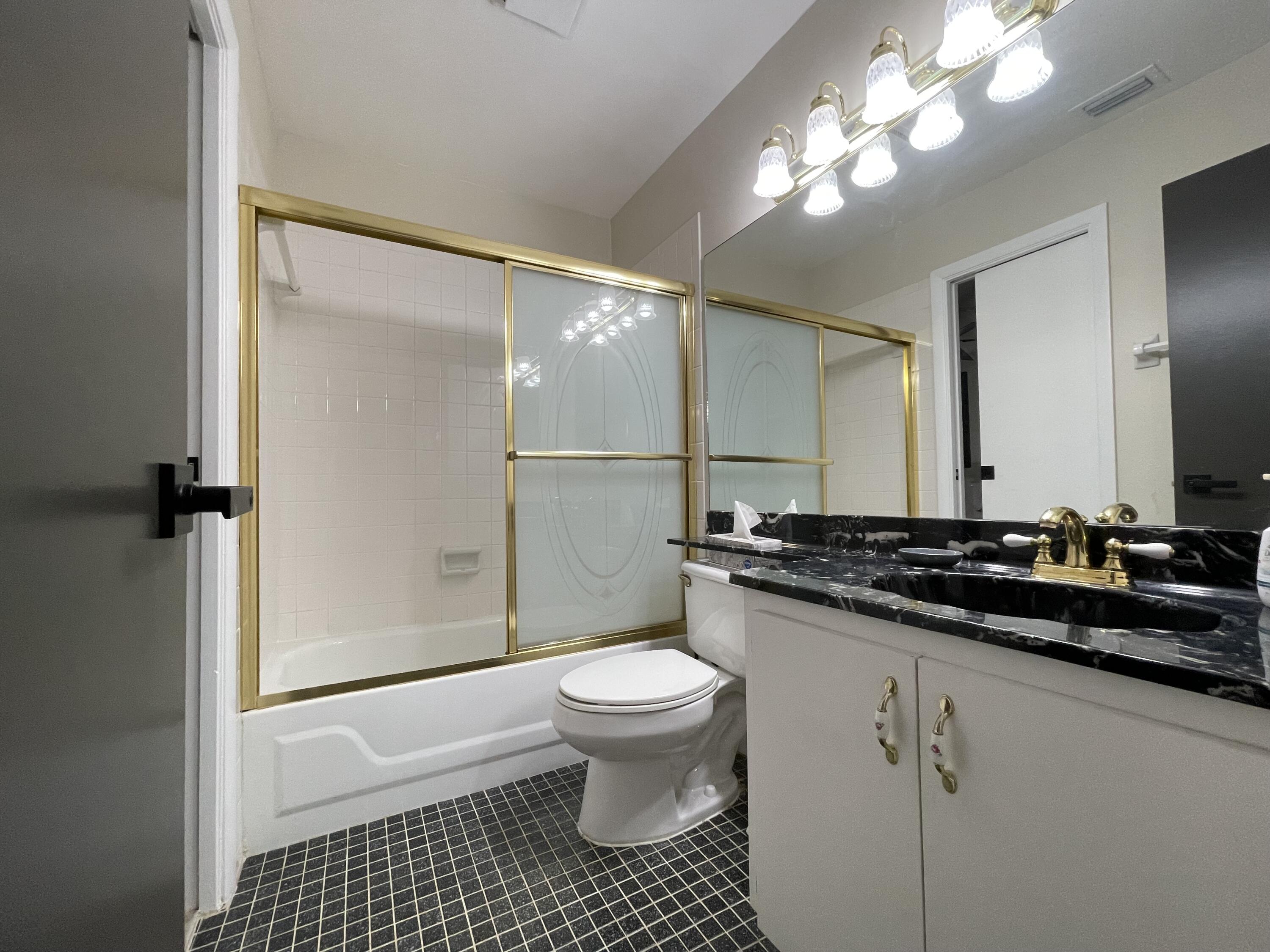 354 Southwest 28th Avenue Delray Beach, FL 33445 - Photo 26 of 54 a bathroom with a sink a toilet a mirror and a shower