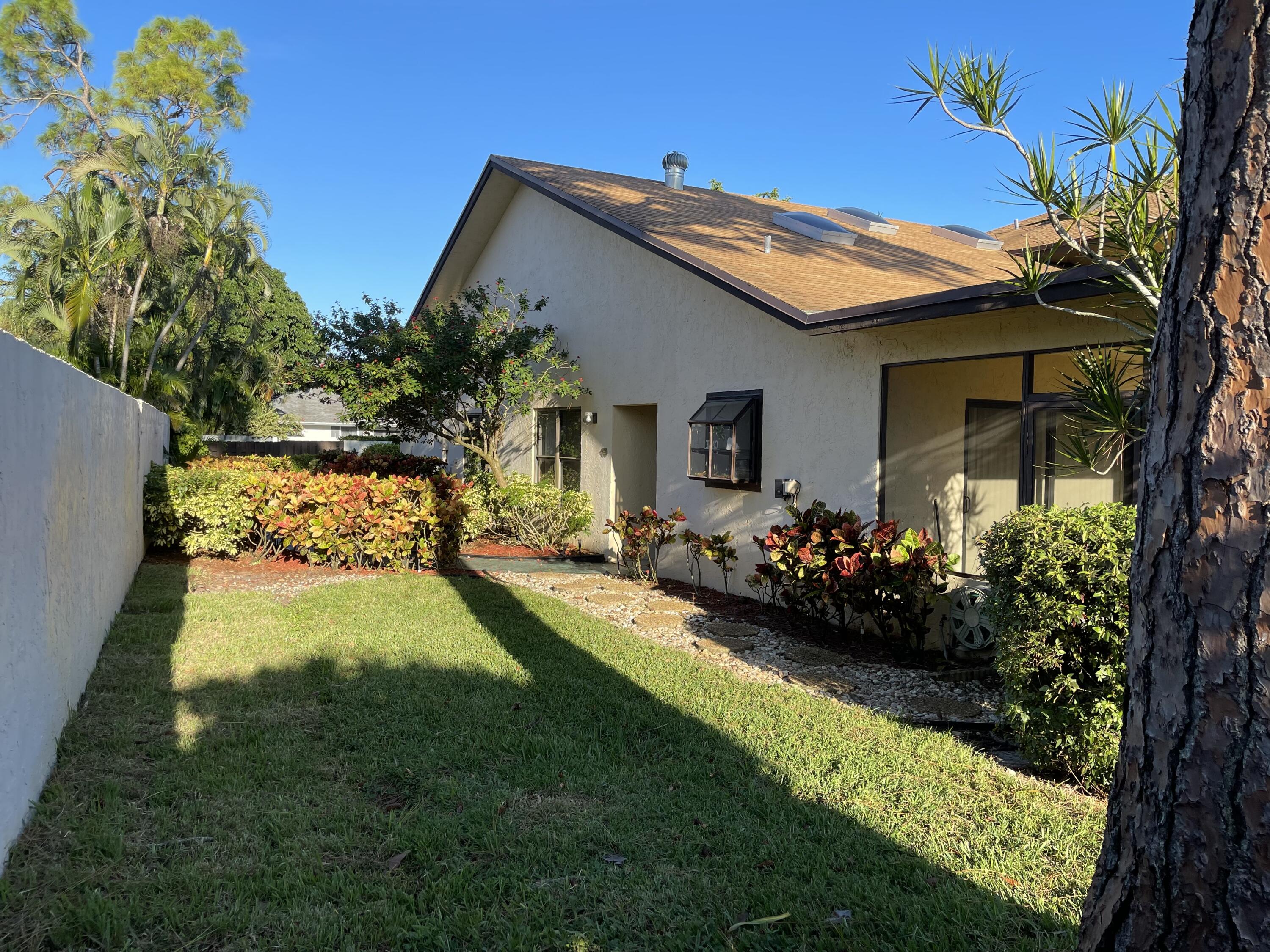 354 Southwest 28th Avenue Delray Beach, FL 33445 - Photo 40 of 54 a view of a house with a big yard potted plants and a large tree