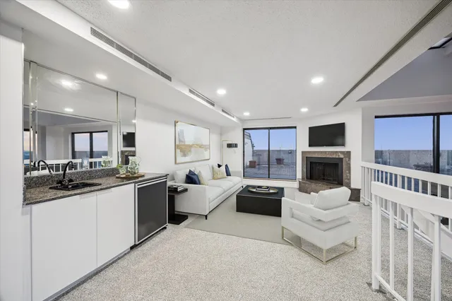 a large living room with stainless steel appliances furniture a rug and a kitchen