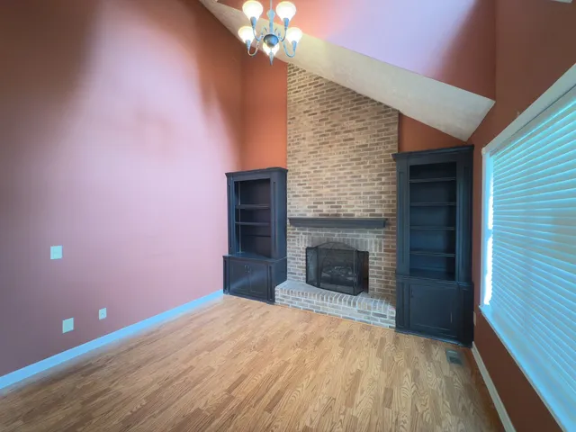 a view of empty room with wooden floor and fireplace