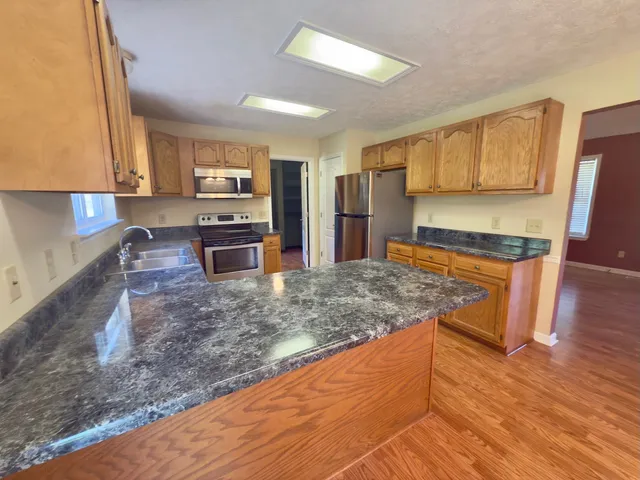 a kitchen with stainless steel appliances granite countertop a sink stove and wooden cabinets