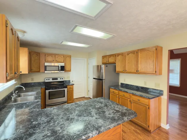 a kitchen with stainless steel appliances granite countertop a stove a sink and a refrigerator