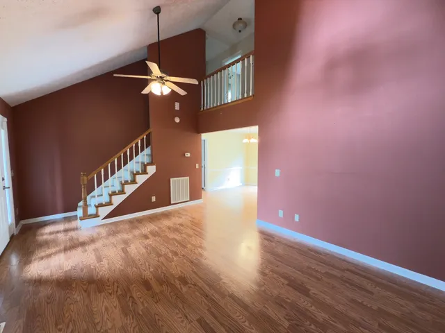 a view of an empty room with a ceiling fan and wooden floor