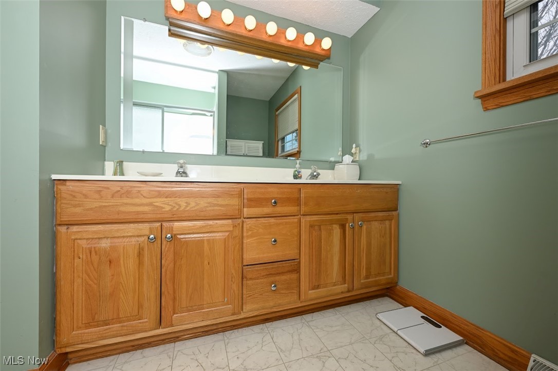 3305 Edington Road Akron, OH 44333 - Photo 24 of 46 Bathroom with visible vents, baseboards, double vanity, marble finish floor, and a sink