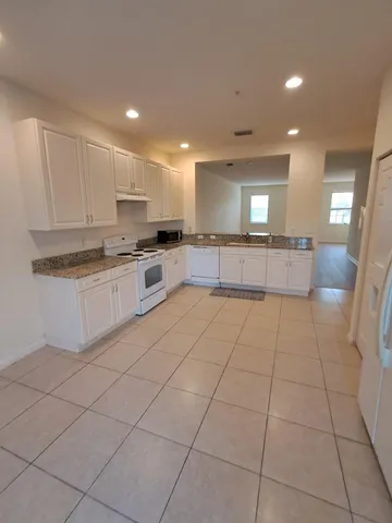 a large kitchen with stainless steel appliances granite countertop a stove a sink a counter top space and cabinets