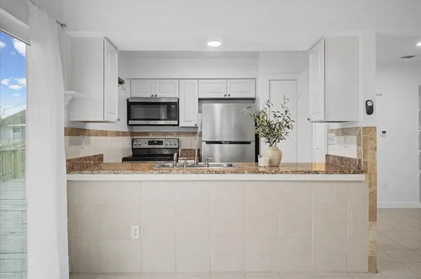 a kitchen with granite countertop a refrigerator and a stove top oven