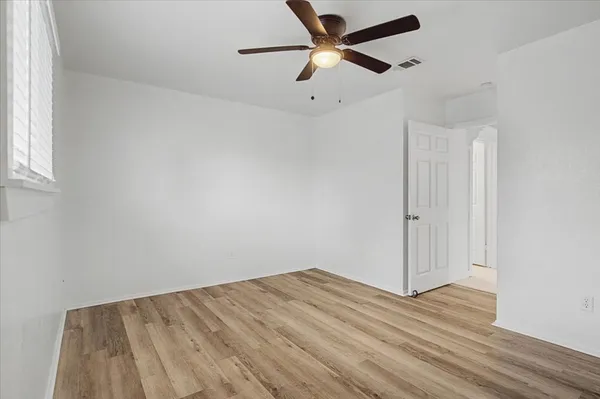 an empty room with wooden floor and a ceiling fan