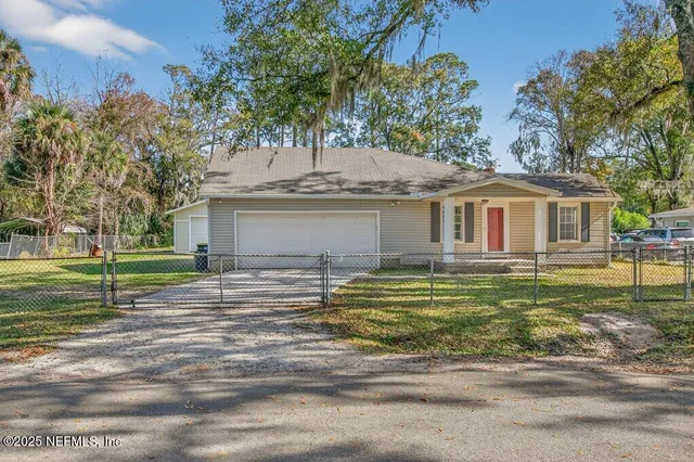 a view of a house with a yard and a large tree