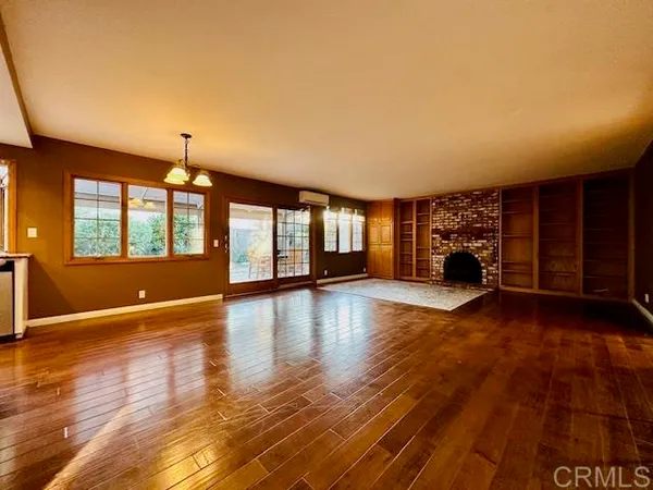 a view of an empty room with window and wooden floor