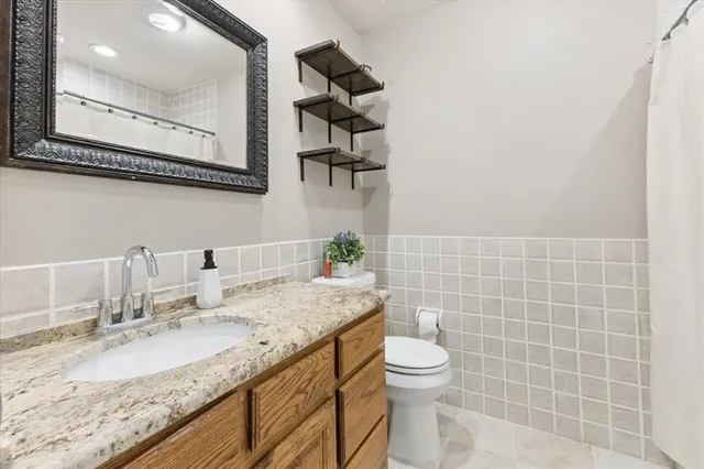 a bathroom with a granite countertop sink a toilet and a mirror