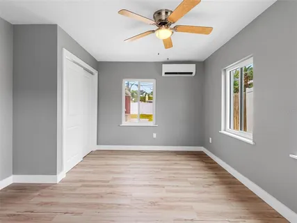 a view of an empty room with wooden floor and a window