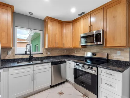 a kitchen with granite countertop cabinets stainless steel appliances a sink and window