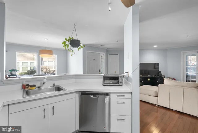 a kitchen with a sink dishwasher a dining table and chairs with wooden floor