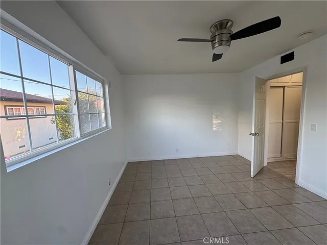 a view of an empty room with closet and a bathroom