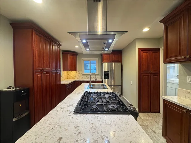 a large kitchen with stainless steel appliances granite countertop a stove a refrigerator and wooden cabinets