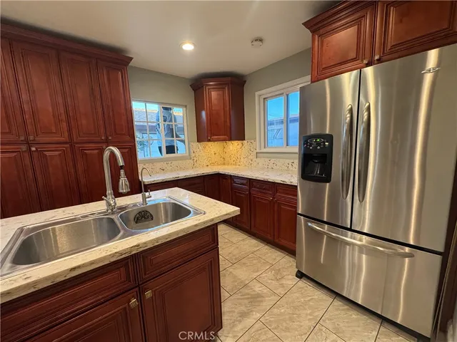 a kitchen with stainless steel appliances granite countertop a refrigerator a sink a stove and a wooden cabinets