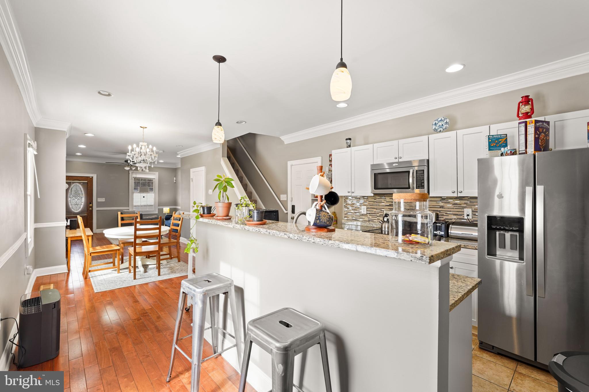 5013 The Alameda Baltimore, MD 21239 - Photo 7 of 24 a kitchen with stainless steel appliances kitchen island granite countertop a refrigerator a stove top oven a sink dishwasher a dining table and chairs with wooden floor