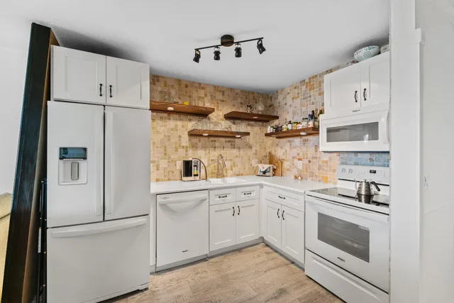 a kitchen with white cabinets and white appliances