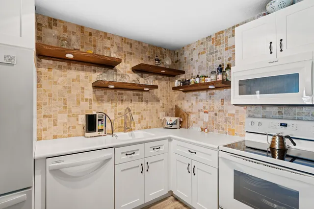 a kitchen with white cabinets and white appliances