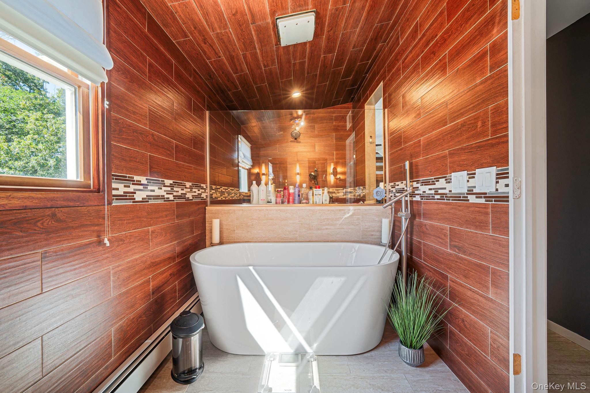 183 Old Country Road Speonk, NY 11972 - Photo 14 of 48 Full bathroom featuring a freestanding bath, tile walls, and a baseboard heating unit