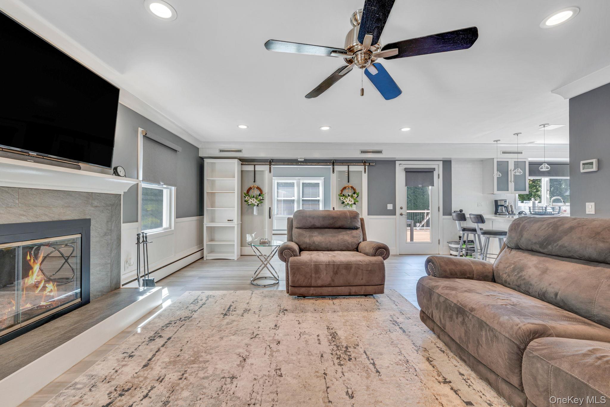 183 Old Country Road Speonk, NY 11972 - Photo 23 of 48 Living area featuring wainscoting, plenty of natural light, ceiling fan, wood finished floors, and a fireplace