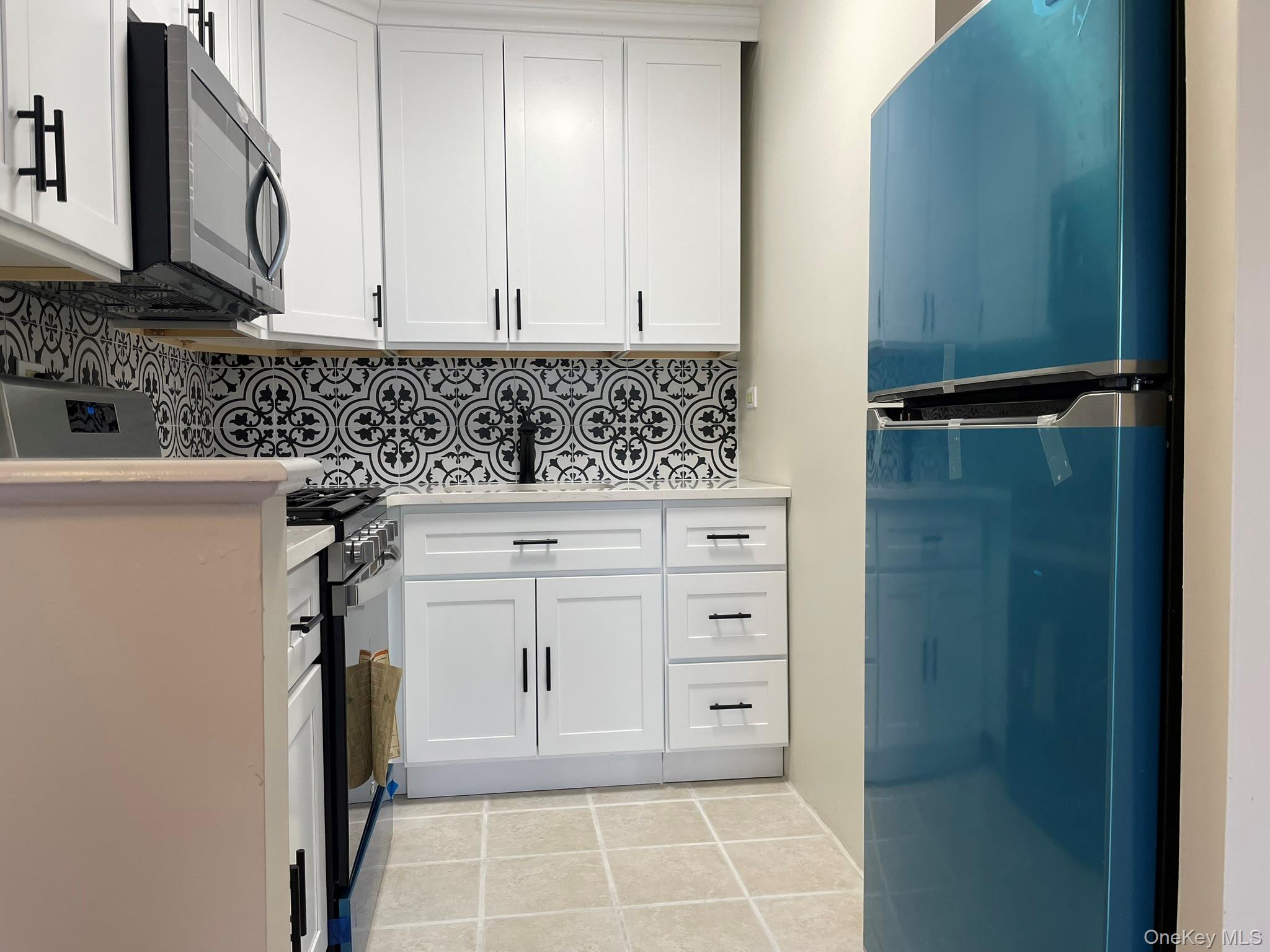 301 West 110th Street, Unit 14F Manhattan, NY 10026 - Photo 6 of 18 Kitchen with light countertops, white cabinetry, fridge, and decorative backsplash