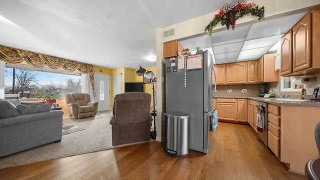 a living room with stainless steel appliances granite countertop furniture a refrigerator a kitchen and a sink