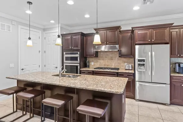 a kitchen with granite countertop a refrigerator and a stove top oven