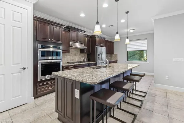 a kitchen with kitchen island a counter top space a sink stainless steel appliances and cabinets