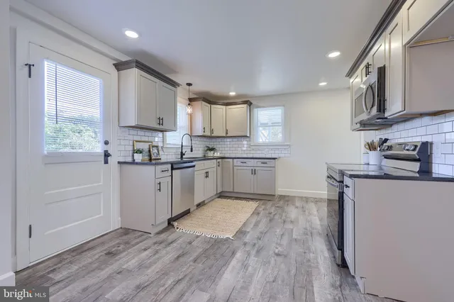 a kitchen with stainless steel appliances granite countertop wooden cabinets a sink a stove a refrigerator and cabinets