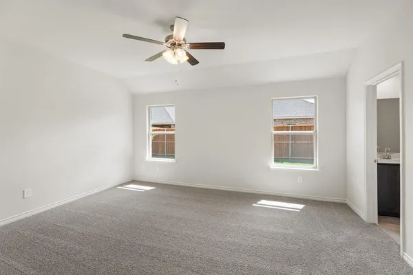 an empty room with windows and fan