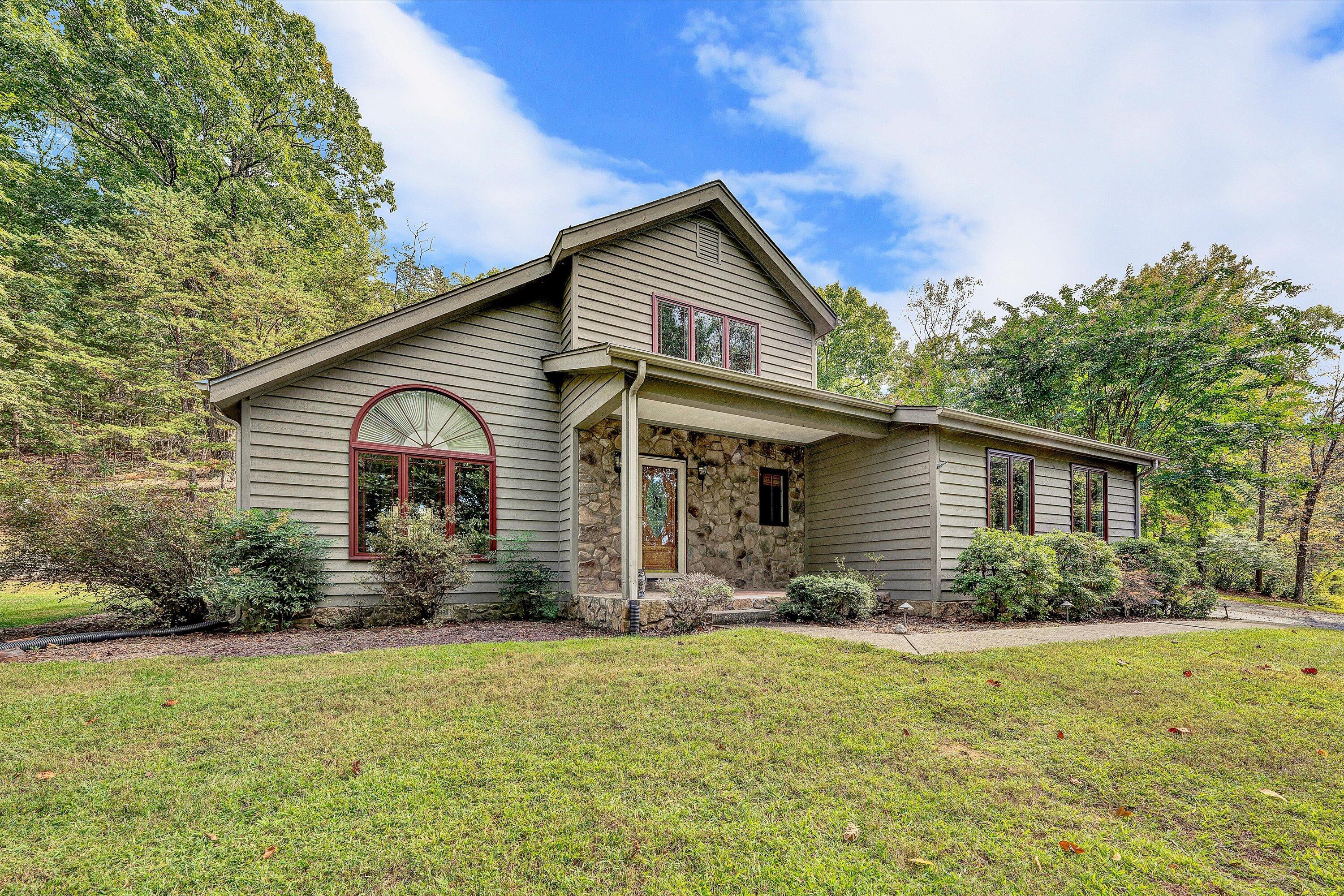 a front view of house with yard and trees in the background