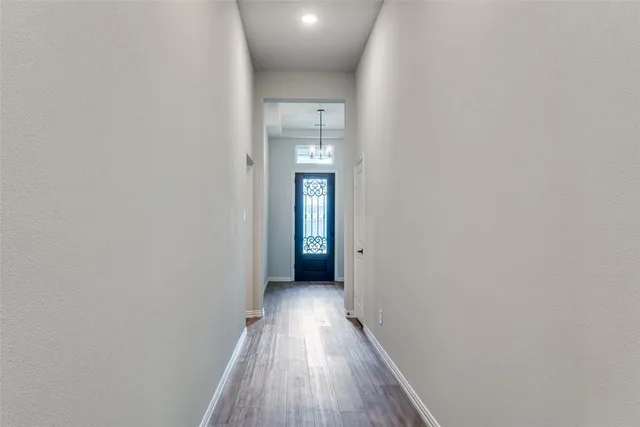 a view of a hallway with wooden floor and a bathroom