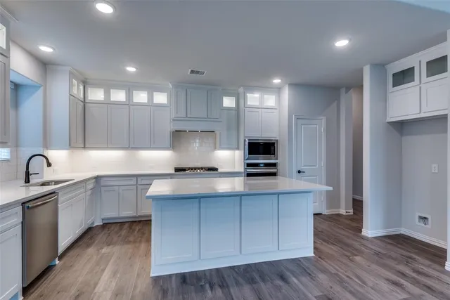 a kitchen with stainless steel appliances a sink stove and wooden cabinets