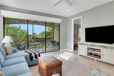 a living room with furniture a flat screen tv and a floor to ceiling window