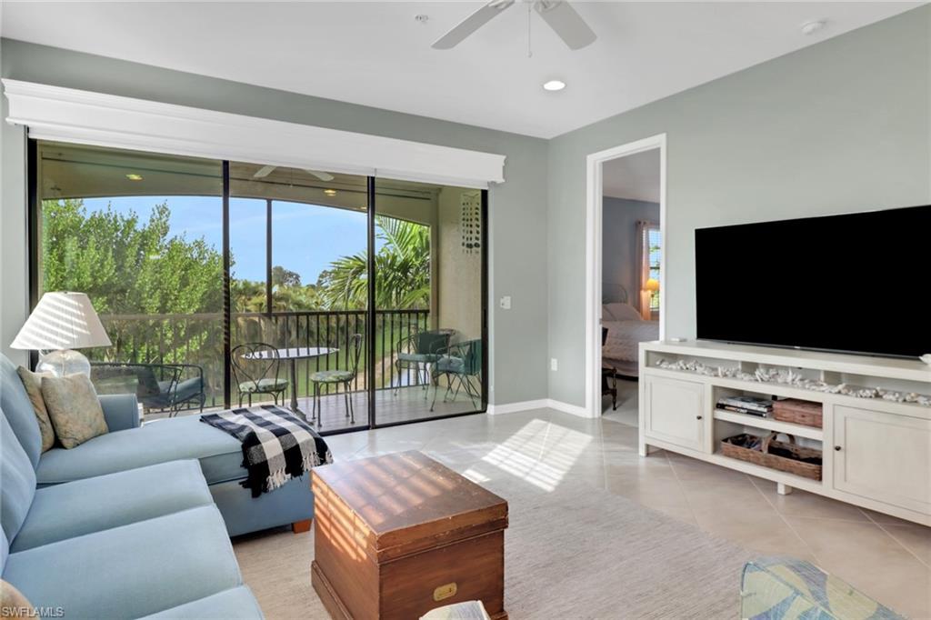 26233 Palace Lane, Unit 201 Bonita Springs, FL 34135 - Photo 11 of 46 a living room with furniture a flat screen tv and a floor to ceiling window