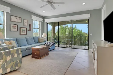 a living room with furniture a flat screen tv and a floor to ceiling window
