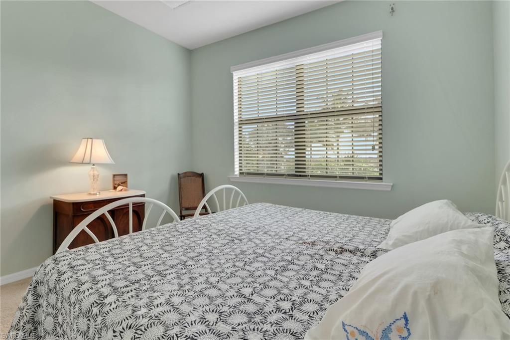 26233 Palace Lane, Unit 201 Bonita Springs, FL 34135 - Photo 20 of 46 a bedroom with a bed and a table lamp