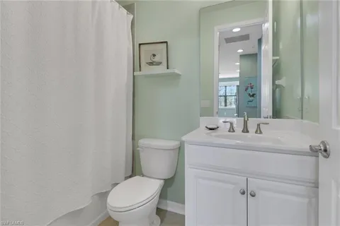 a bathroom with a toilet sink vanity and mirror
