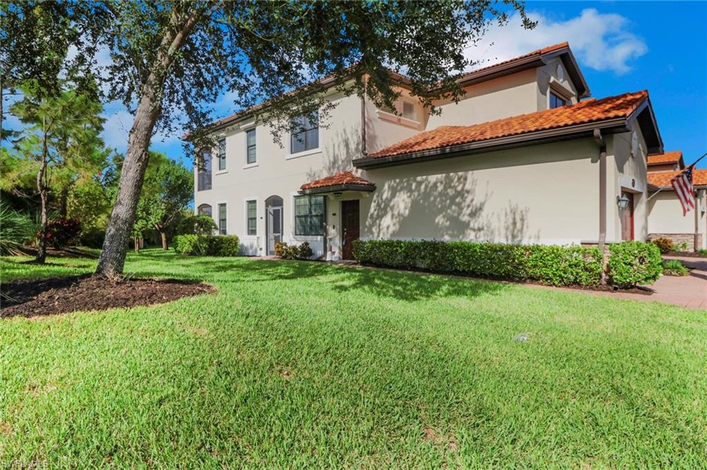 26233 Palace Lane, Unit 201 Bonita Springs, FL 34135 - Photo 29 of 46 a view of a white house with a big yard and large tree