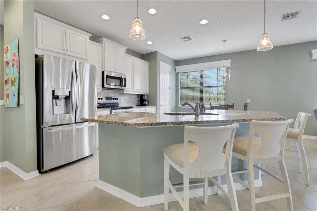 26233 Palace Lane, Unit 201 Bonita Springs, FL 34135 - Photo 6 of 46 a kitchen with stainless steel appliances granite countertop a white cabinets and a refrigerator