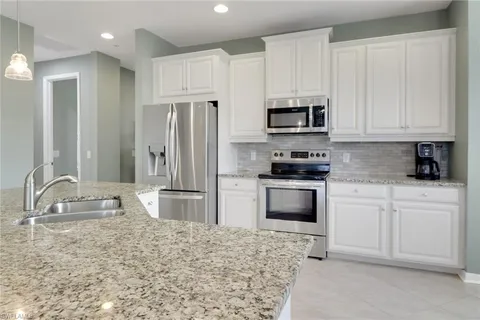 a kitchen with granite countertop a refrigerator sink and microwave