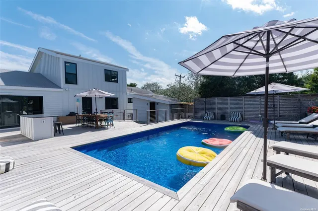 a swimming pool with outdoor seating and yard in the back