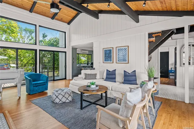 a living room with furniture large windows and wooden floor