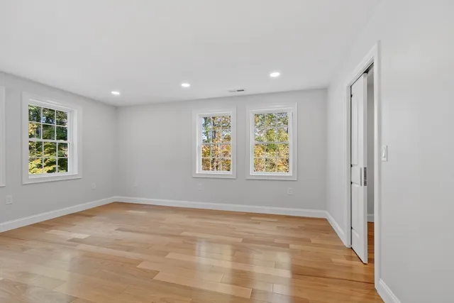 an empty room with wooden floor and windows