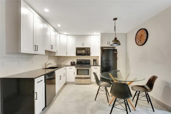 a kitchen with stainless steel appliances granite countertop a stove top oven a sink dishwasher a dining table and chairs with wooden floor