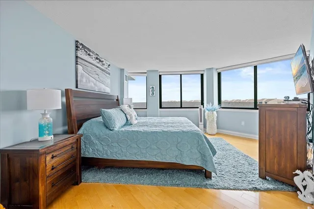 a bedroom with a bed and dresser with wooden floor