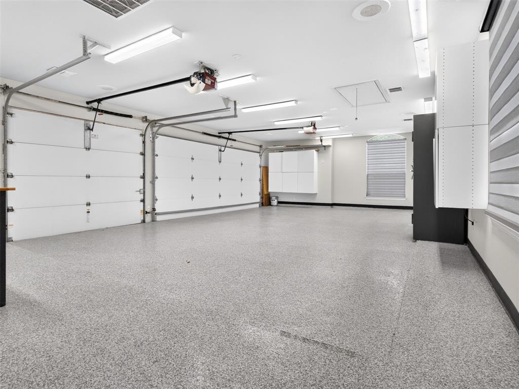 6809 Cedar Ridge Court Plano, TX 75093 - Photo 33 of 38 Two-car garage featuring segmented overhead doors, epoxy flooring, built-in cabinetry, and integrated lighting