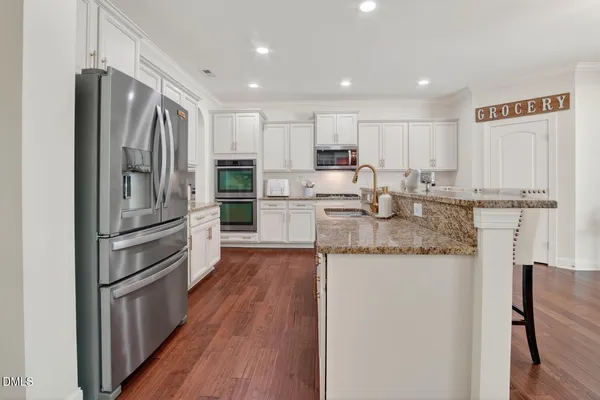 a kitchen with granite countertop white cabinets and stainless steel appliances